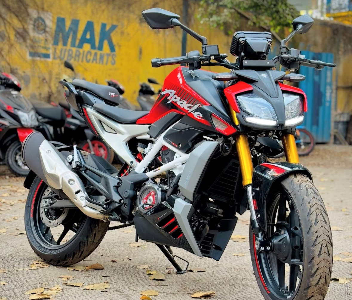 Red, white and black TVS Apache RTR 310 naked performance bike parked on a roadside with golden upside-down forks and LED headlamp cluster
