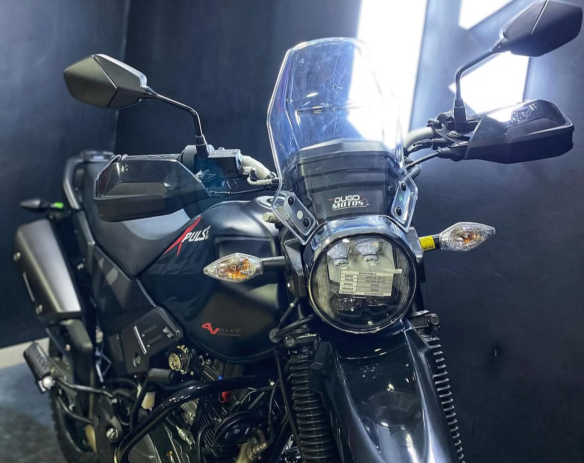 Matte black Hero Xpulse adventure bike photographed from the front showing its round LED headlamp, tall clear windscreen and knuckle guards